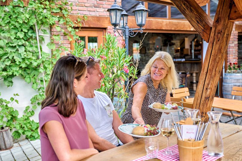 Szene im Rädle Marte,,Wirtin bringt Teller mit Essen an den Tisch"