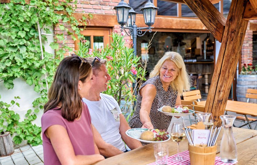 Szene im Rädle Marte,,Wirtin bringt Teller mit Essen an den Tisch"