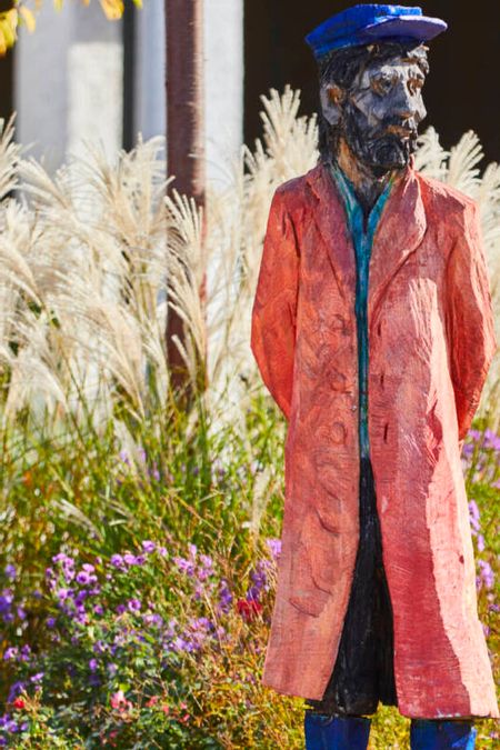 Holzfigur von Clemens Heinl auf dem Kirchplatz, sie stellt einen Schiffsanbinder von ehemals dar