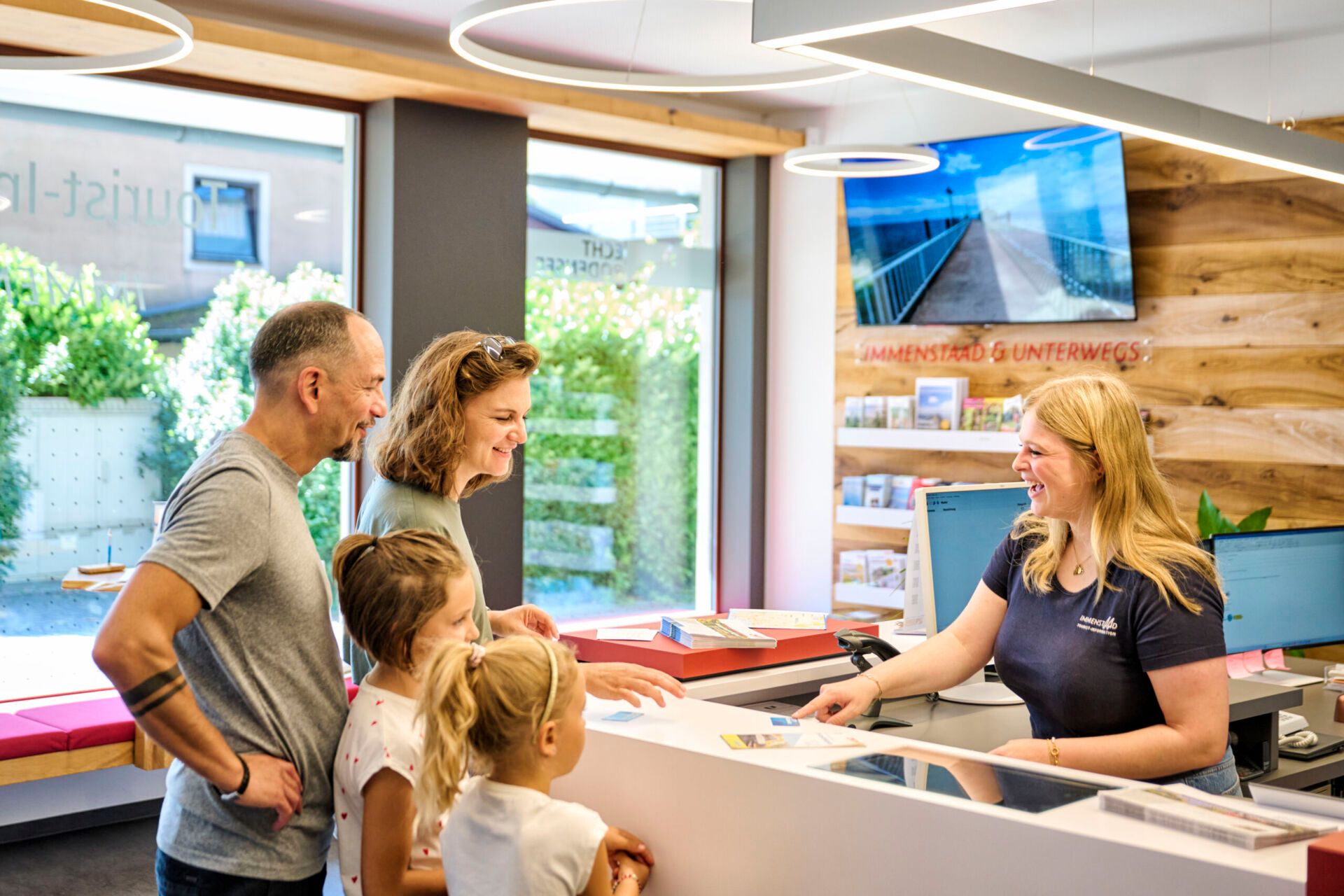 Einer Familie wird an einem Counter die Gästekarte überreicht