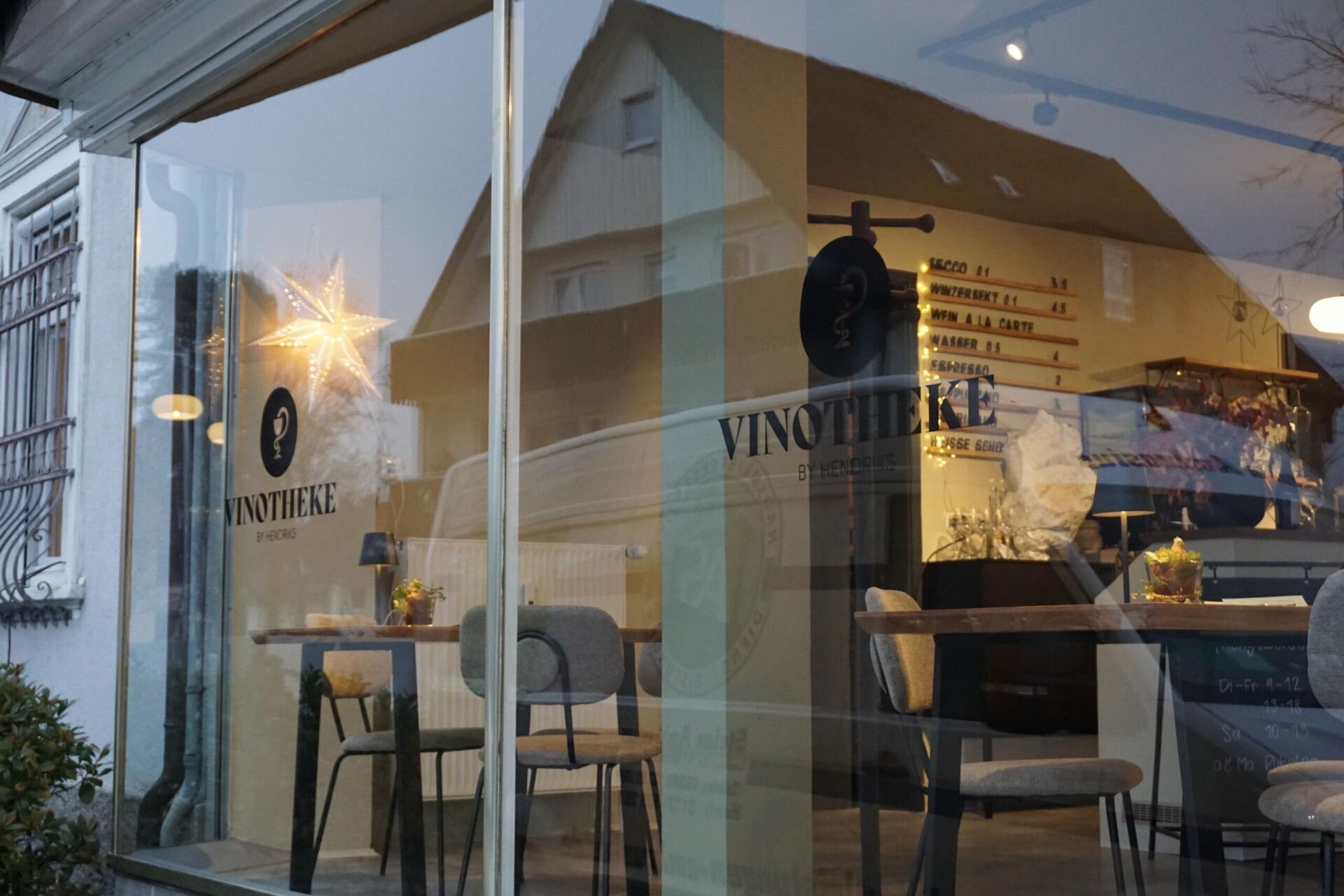 Schaufenster der Vinotheke, es sind im inneren Tische und Stühle sichtbar