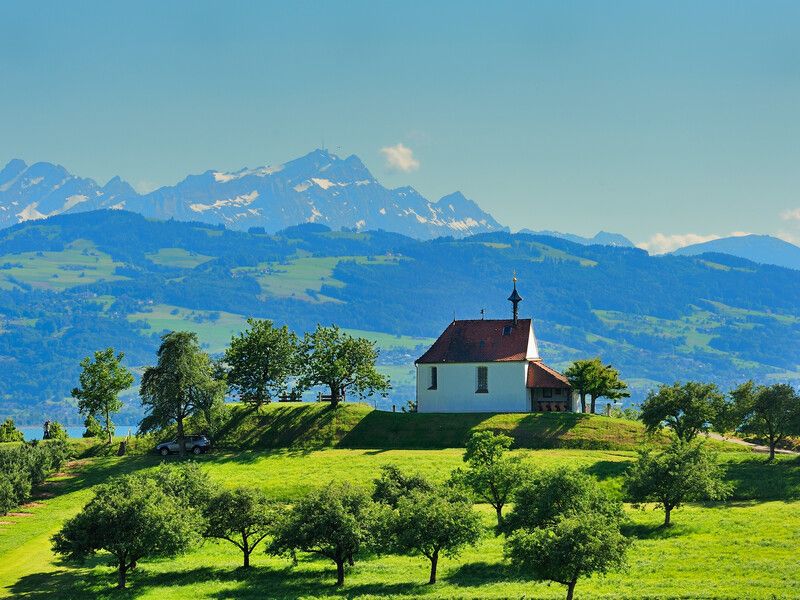 Antoniuskapelle in Selmnau. Im Vordergrund sind Felder zu sehen. Im Hintergrund die verschneite Bergwelt.
