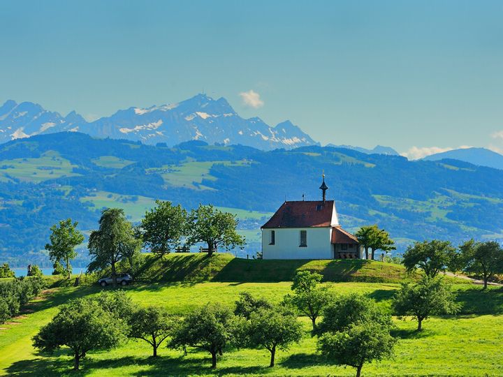 Antoniuskapelle in Selmnau. Im Vordergrund sind Felder zu sehen. Im Hintergrund die verschneite Bergwelt.