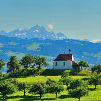 Antoniuskapelle in Selmnau. Im Vordergrund sind Felder zu sehen. Im Hintergrund die verschneite Bergwelt.