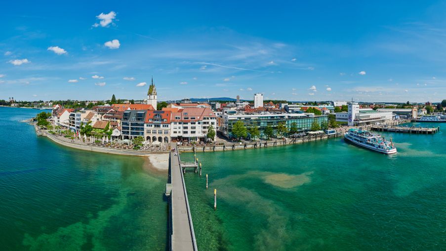 Luftaufnahme Friedrichshafen mit Hafeneinfahrt. Im Vordergrund der Bodensee.
