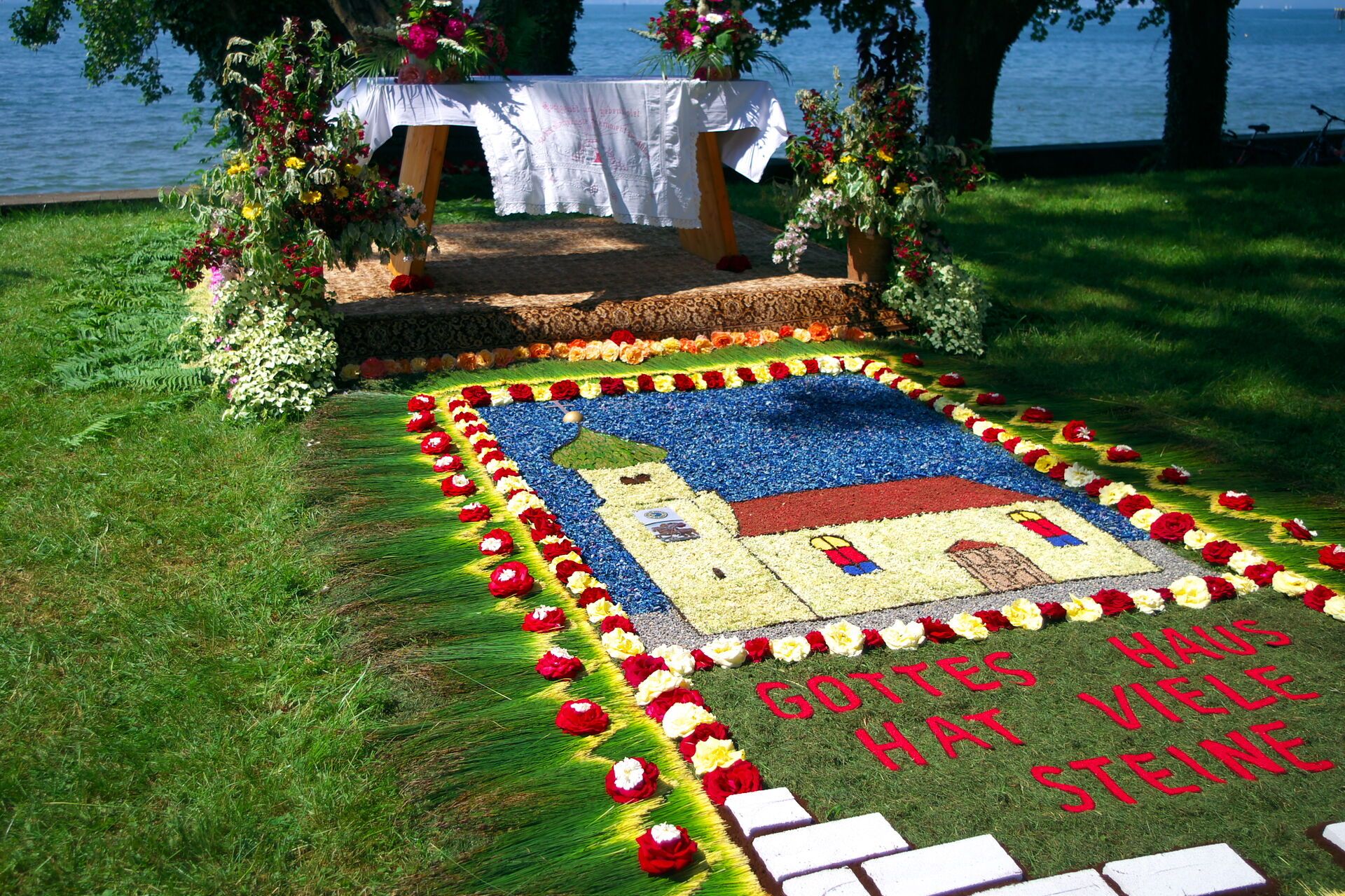Blumenteppich auf der Gamswiese in Wasserburg an Fronleichnam. Mit der Aufschrift Gottes Haus hat viele Steine.