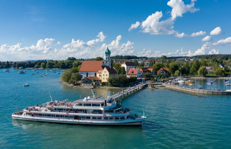 Die Halbinsel in Wasserburg mit Schiffsanleger und einem anlegendem Schiff umringt vom See.
