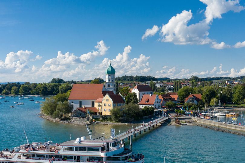 Die Halbinsel in Wasserburg mit Schiffsanleger und einem anlegendem Schiff umringt vom See.