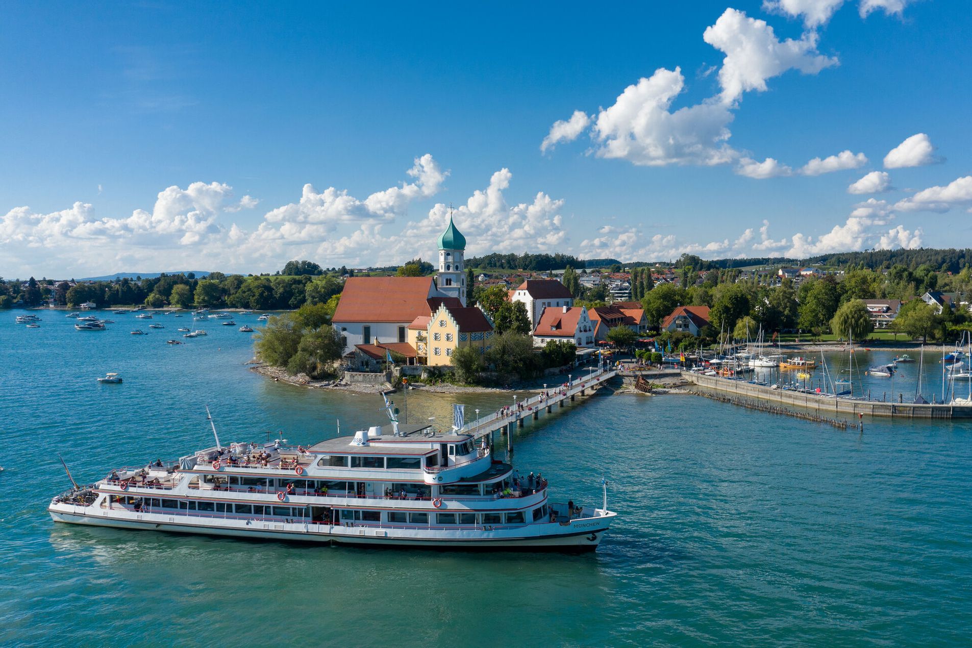 Die Halbinsel in Wasserburg mit Schiffsanleger und einem anlegendem Schiff umringt vom See.