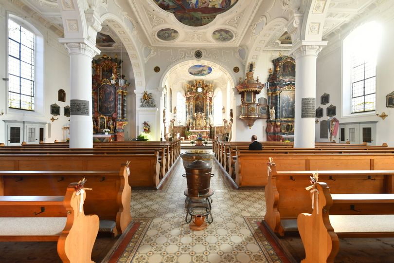 Innenansicht St. Georgskirche mit Bänken, Säulen und verzierter Decke.