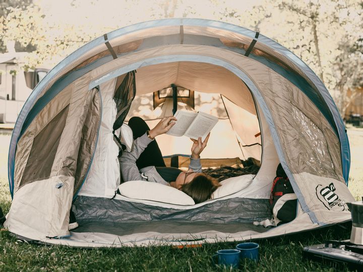 Eine Person liegt im Zelt und ließt ein Buch.