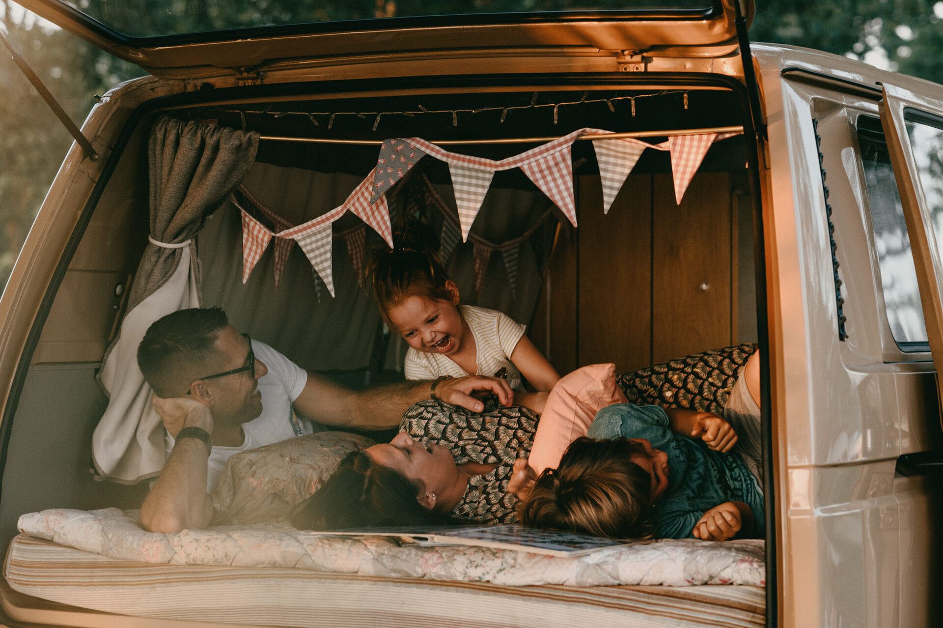 Eine Familie mit zwei Kindern liegt in einem Campingbus und hat eine spaßige Zeit.