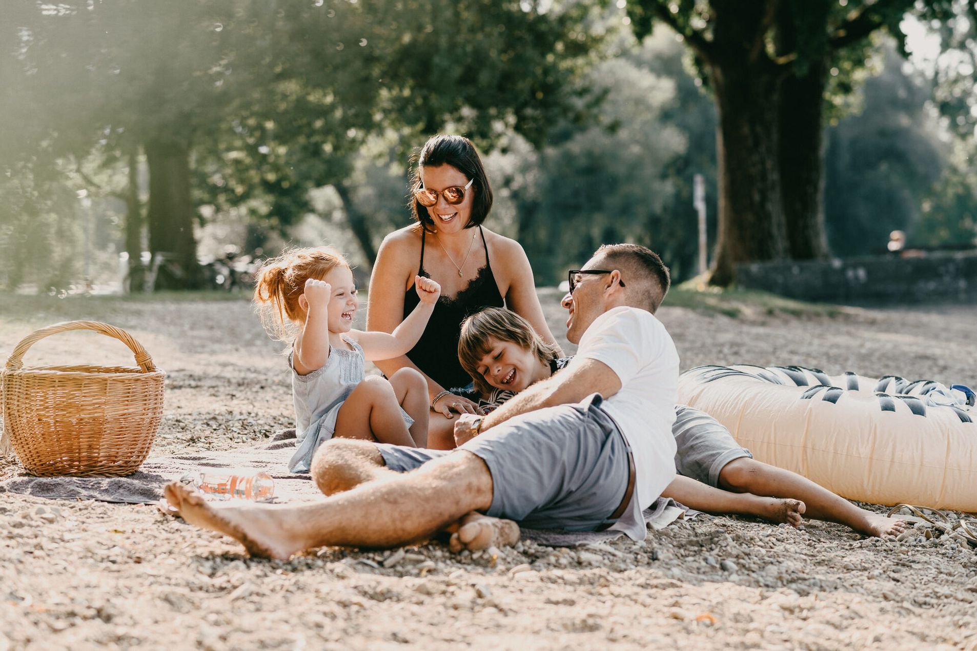 Familie mit zwei Kindern beim Picknick in einem Park.