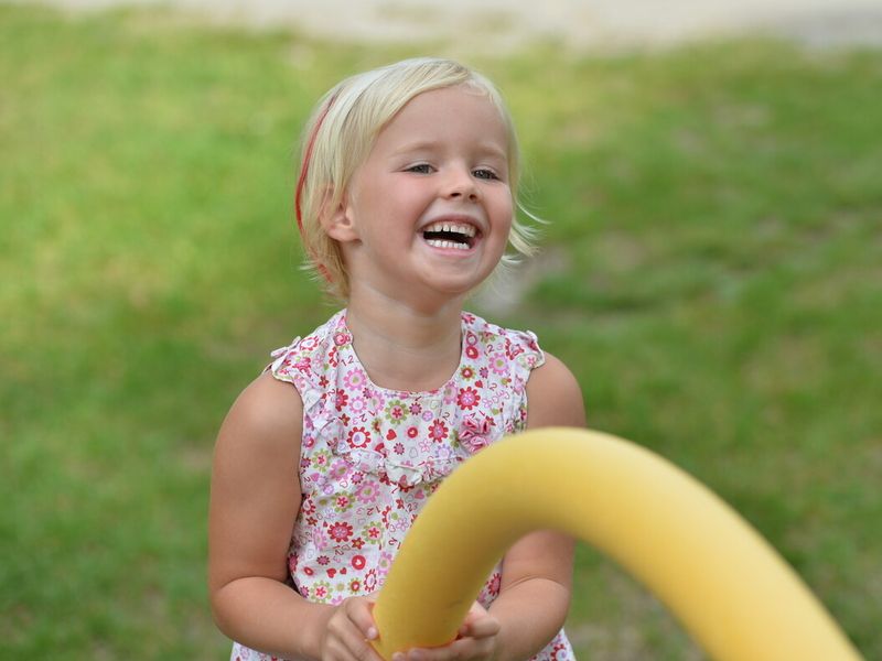 Ein lachendes Mädchen, das mit einem Wasserspielezeug spielt.