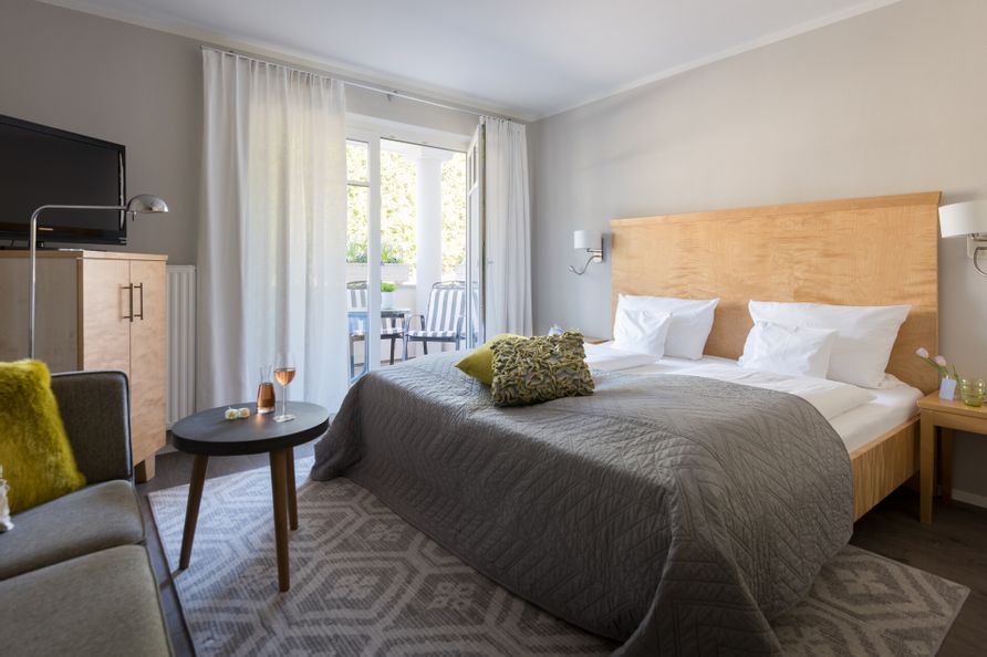 Zimmerinnenansicht von einem Hotel Schlafzimmer mit Doppelbett und einem Balkon.