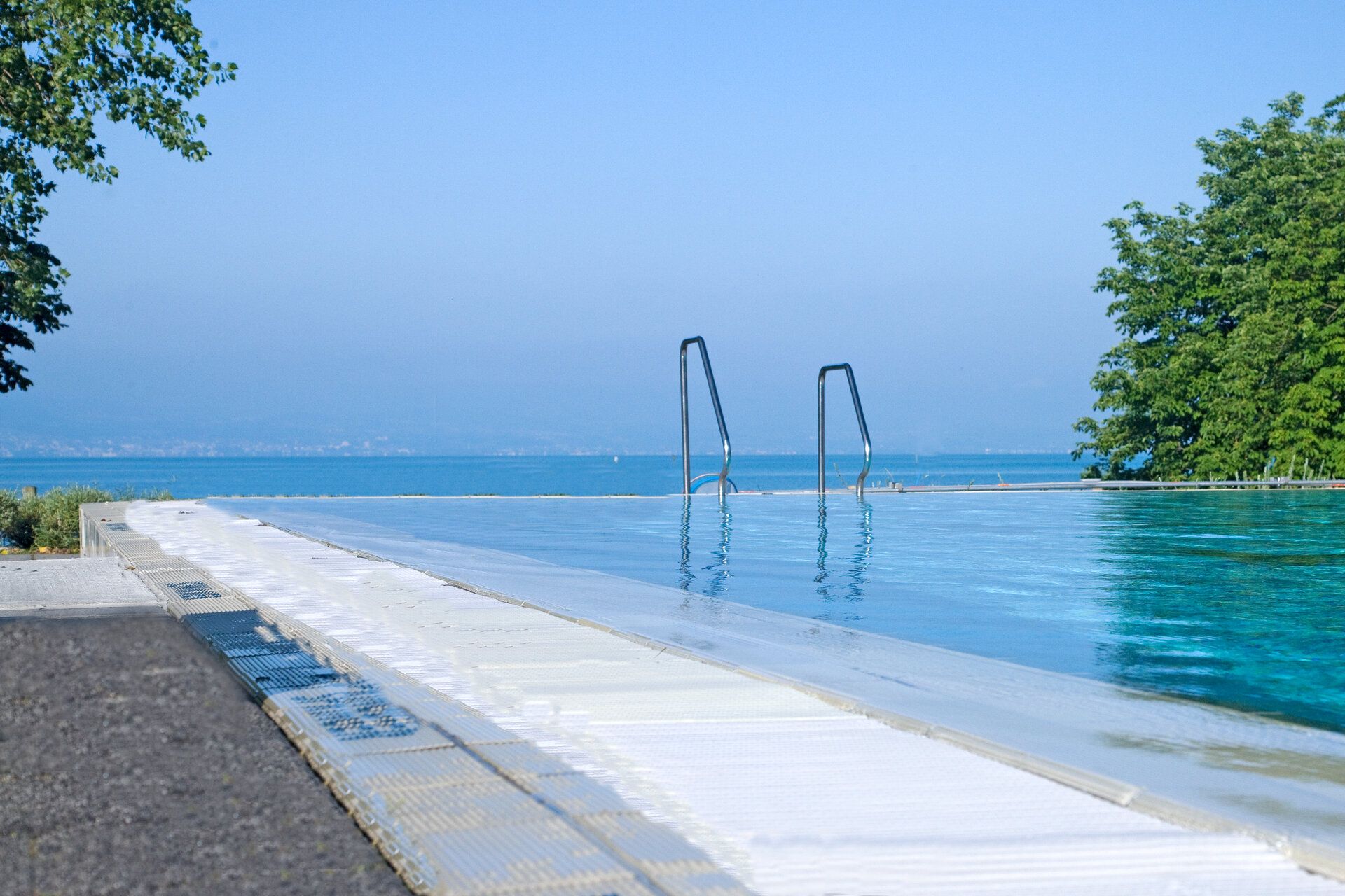 Schwimmbecken im Freibad Aquamarin in Wasserburg. Im Hintergrund ist der Bodensee zu sehen.