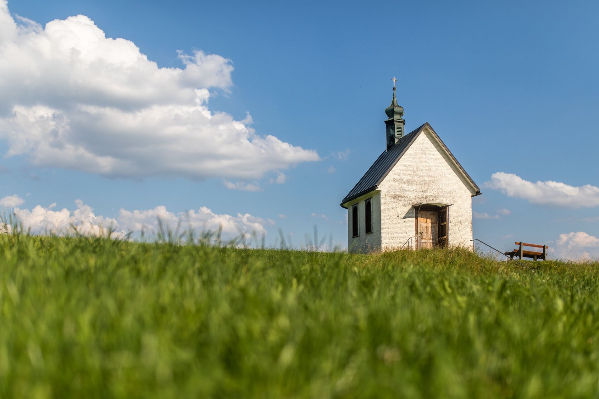 Eine Kapelle in mitten von grün und einem blauen Himmel.