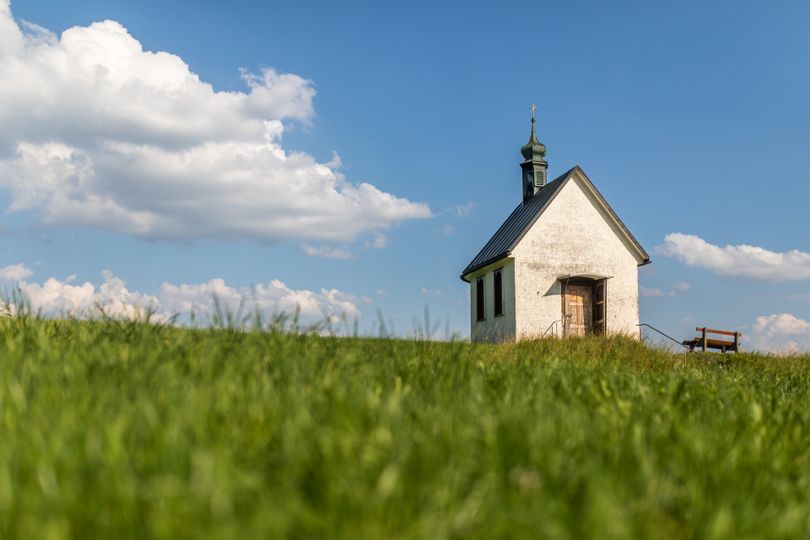 Eine Kapelle in mitten von grün und einem blauen Himmel.