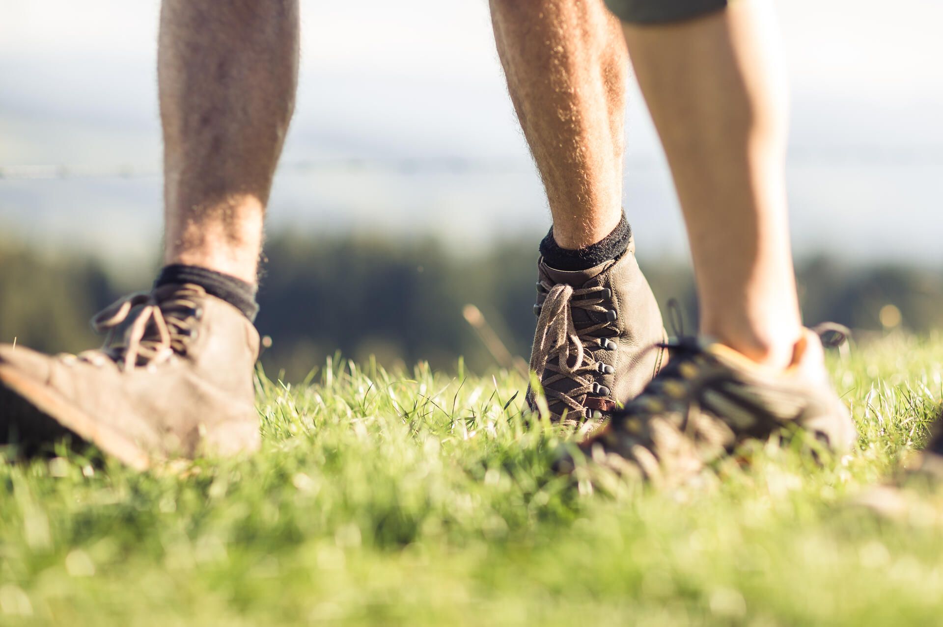 Füße mit Wanderschuhen im Gras zu sehen,