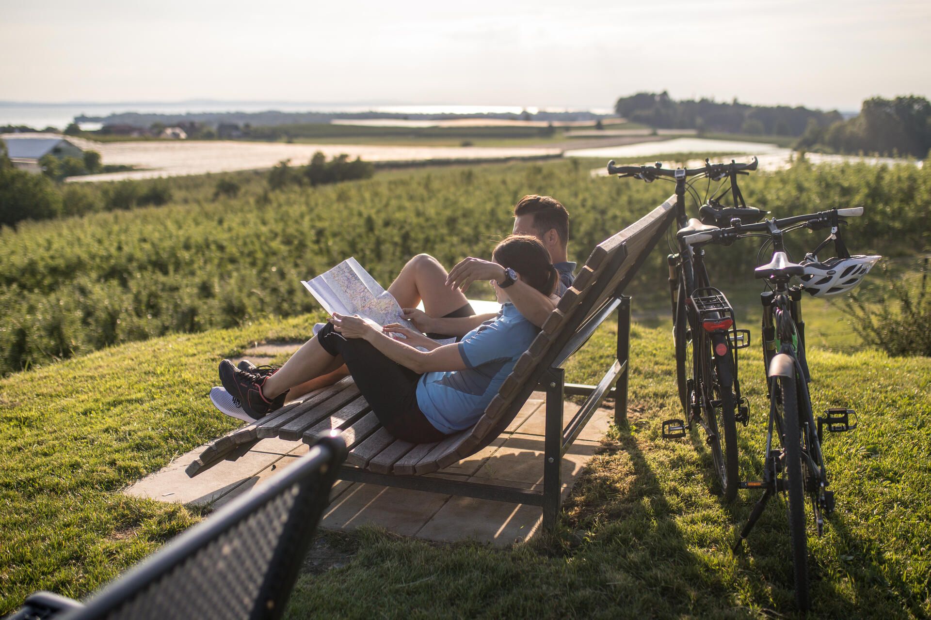 Ein Pärchen sitzt auf einer Bank an der Antoniuskapelle in Selmnau und hält eine Rad karte in der Hand. Die Fahrräder lehnen an der Bank an.