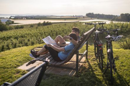 Ein Pärchen sitzt auf einer Bank an der Antoniuskapelle in Selmnau und hält eine Rad karte in der Hand. Die Fahrräder lehnen an der Bank an.