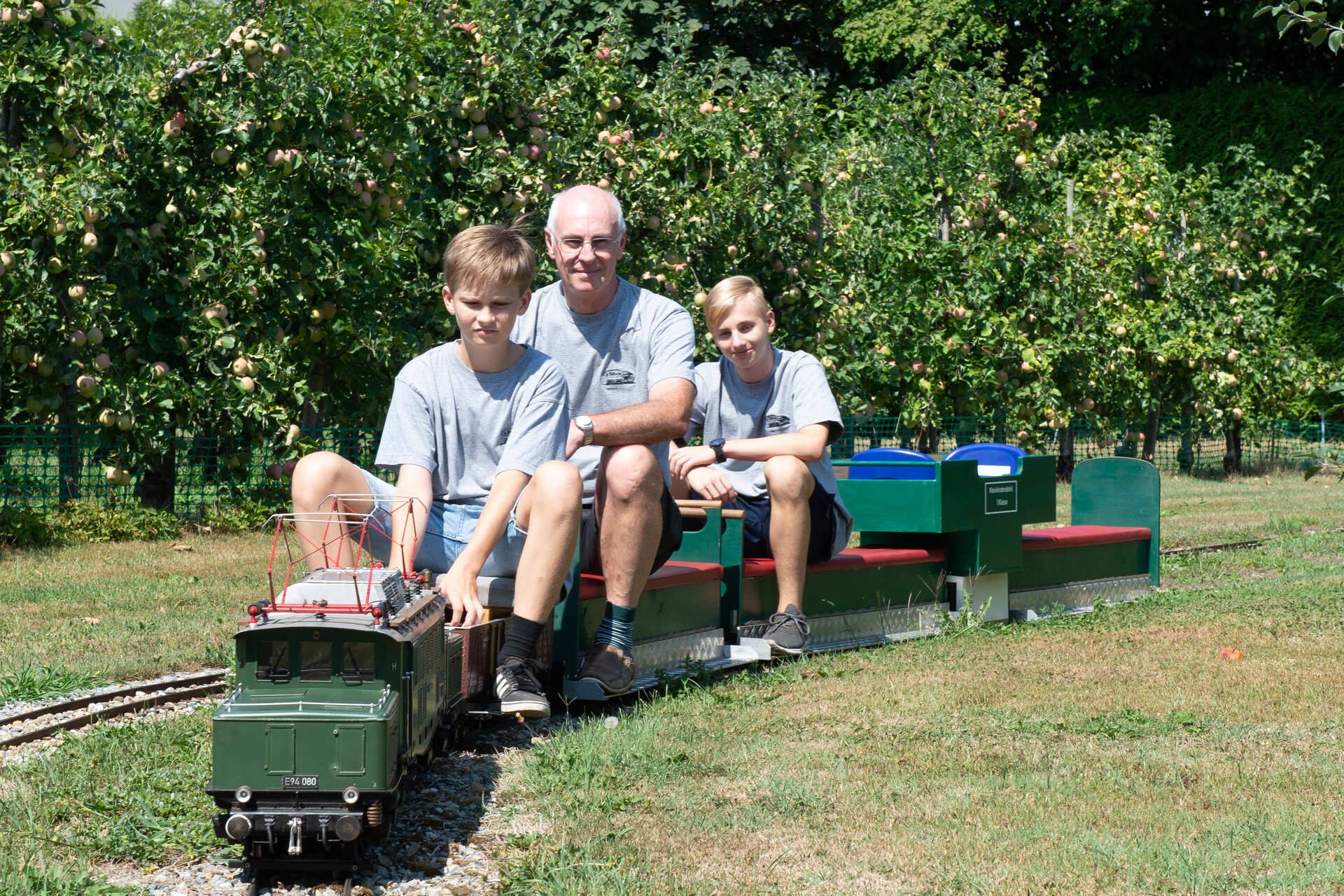 Ehrles Garteneisenbahn. Drei Personen auf der Garteneisenbahn.