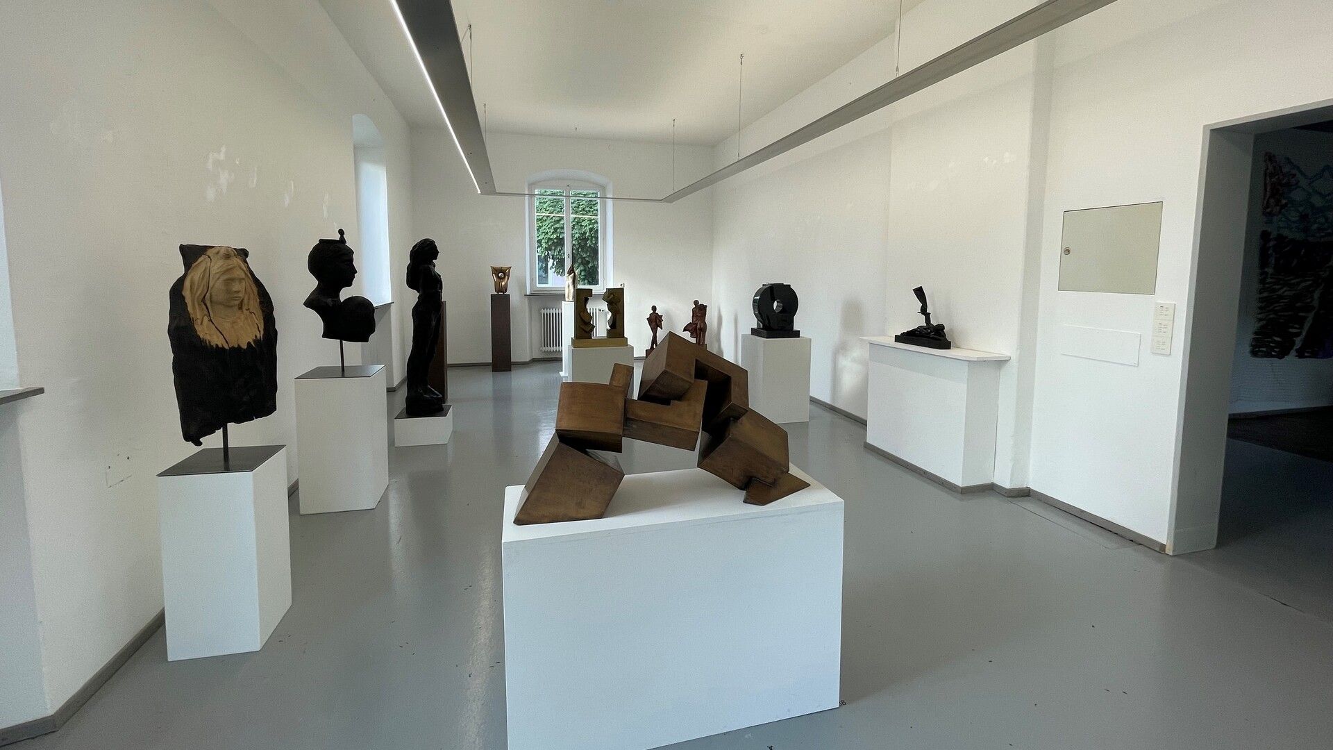 Kunst im KUBA Wasserburg. Das Bild zeigt den Ausstellungsraum mit verschiedenen ausgestellten Skulpturen und Kunstgegenständen.