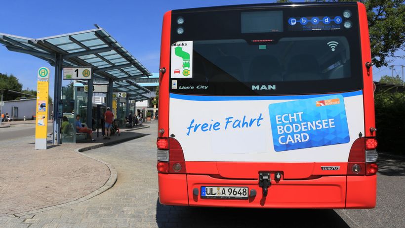 Die Hinteransicht eine Buses, der an einer Bushaltestelle anhält.