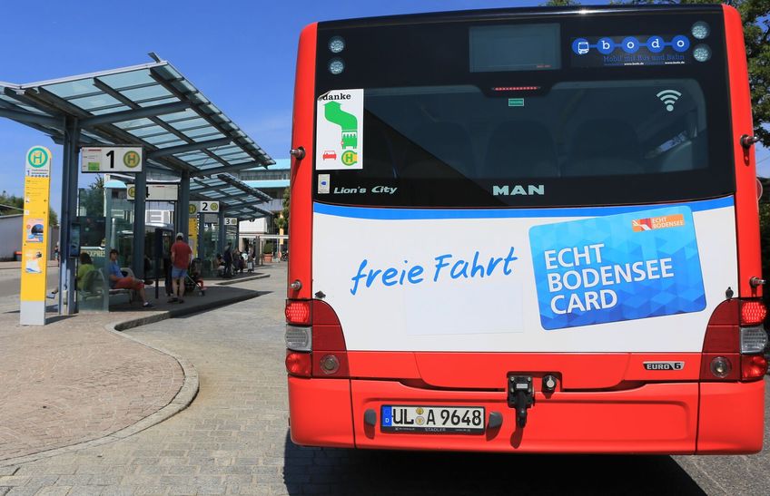 Die Hinteransicht eine Buses, der an einer Bushaltestelle anhält.
