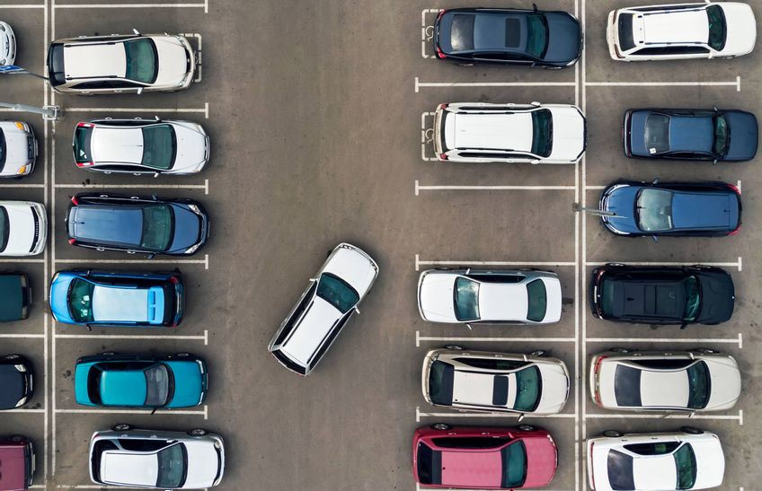 Ein Parkplatz mit mehreren Autos. ein Auto parkt in eine Parklücke ein
