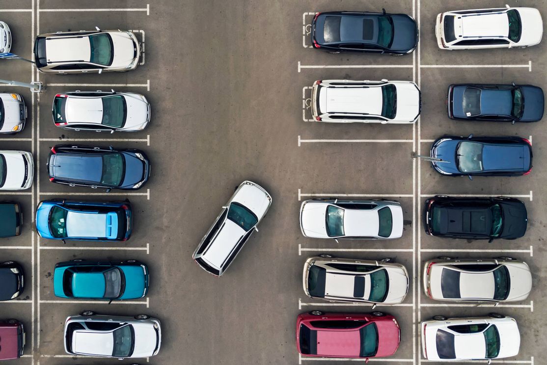 Ein Parkplatz mit mehreren Autos. ein Auto parkt in eine Parklücke ein
