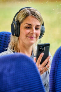 Eine Frau, die im Bus sitzt und ihr Handy in der Hand hält und den Bodensee Podcast anhört.