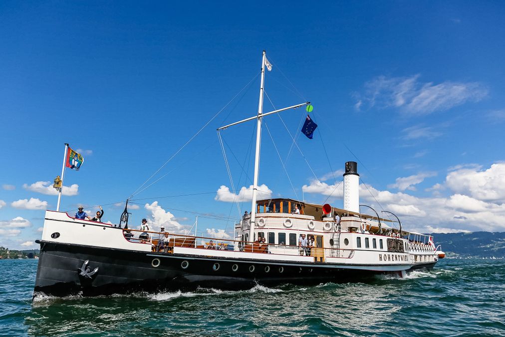 Das Dampfschiff Hohentwiel fährt auf dem Bodensee im Hintergrund Bergpanorama