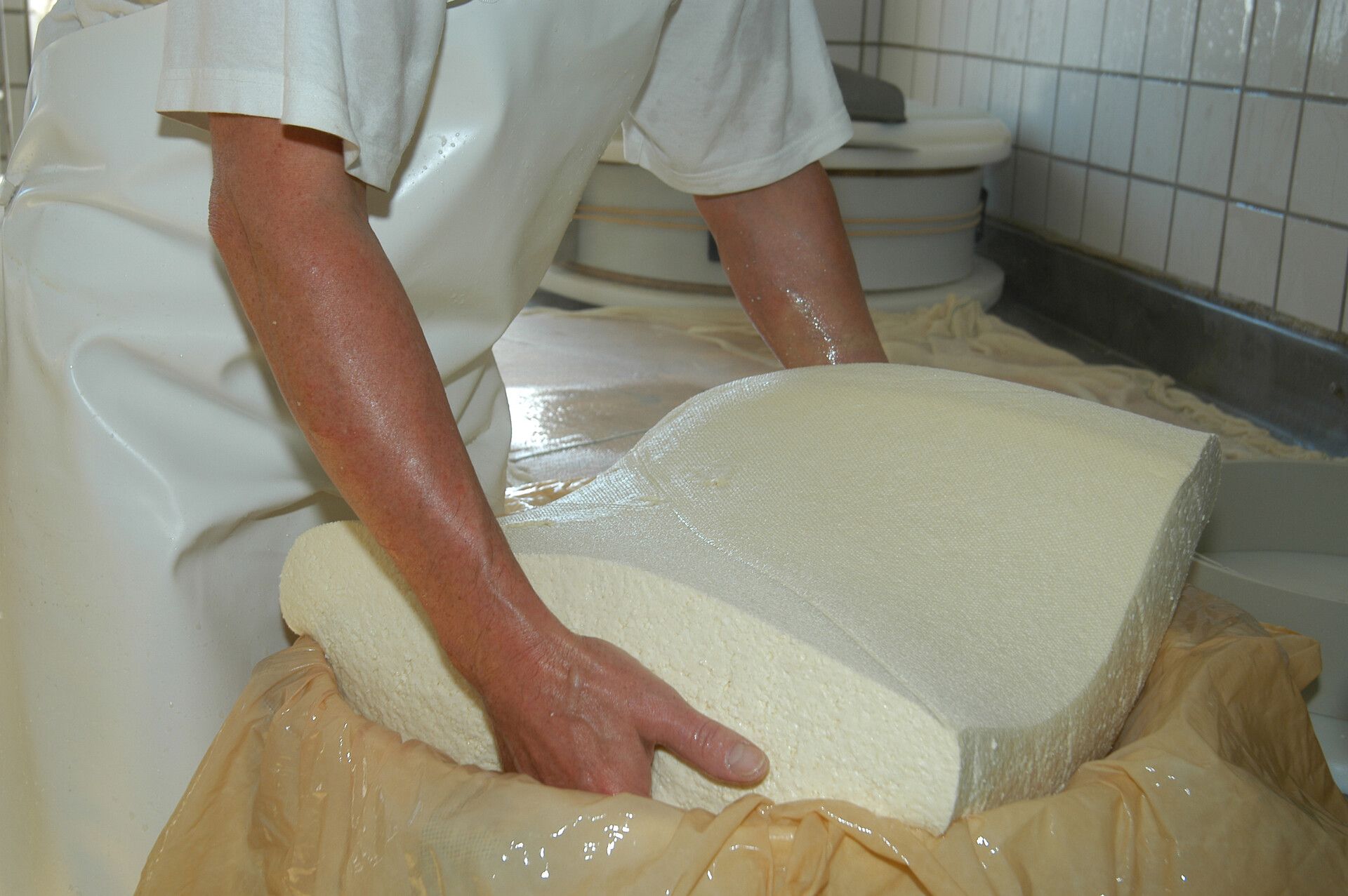 Ein Mann der in einer Sennerei Käse Produziert und verarbeitet