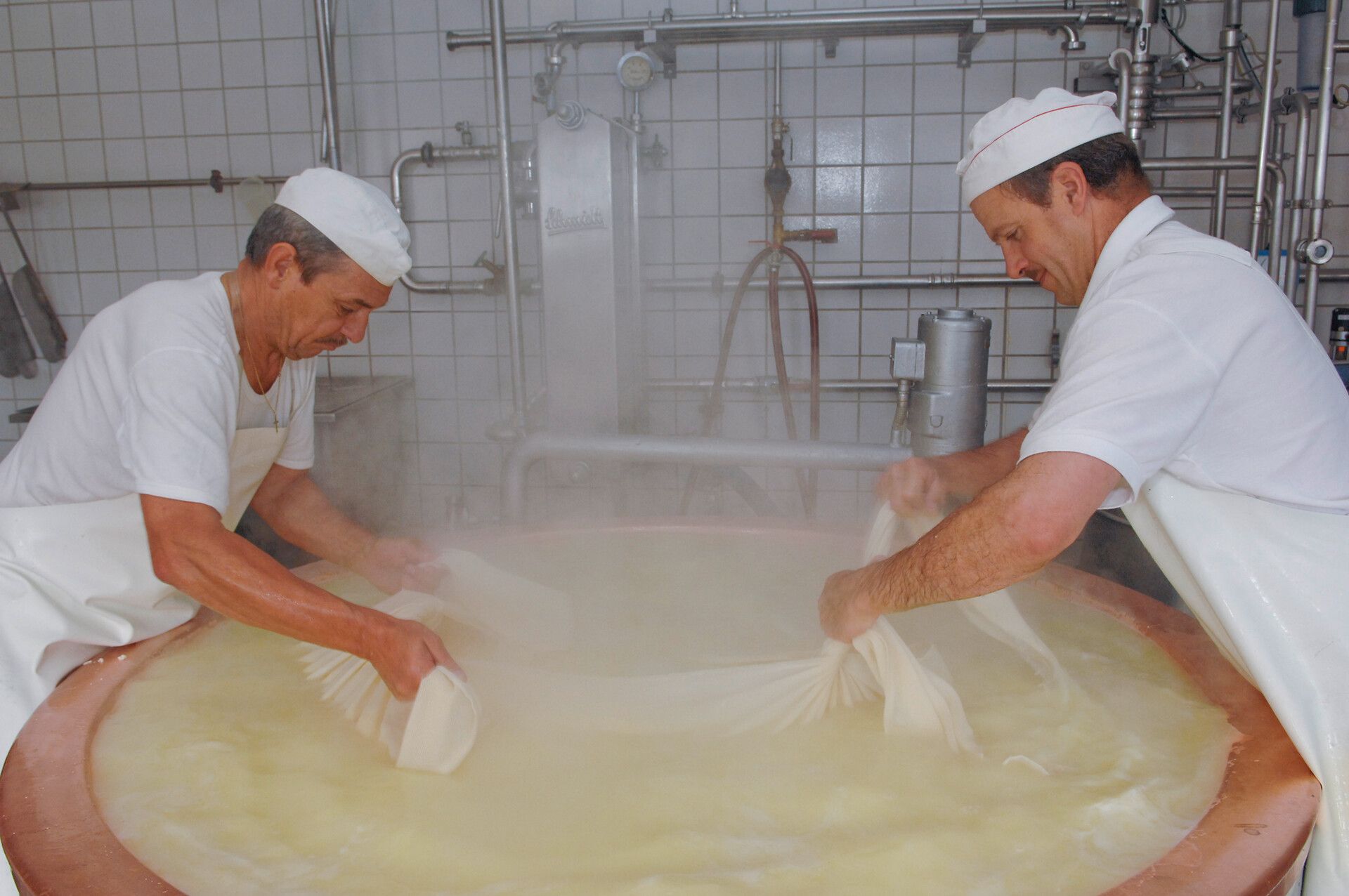 Zwei Männer die in einer Sennerei Käse produzieren