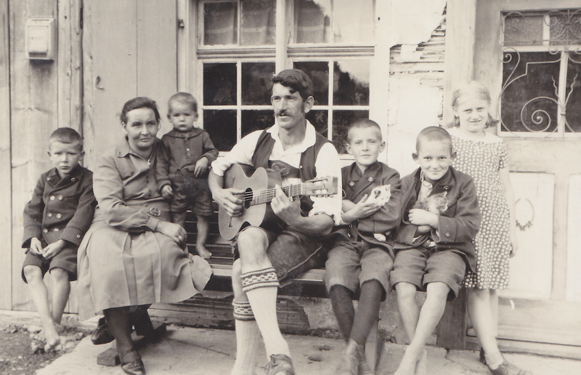 Max Freudig zupft auf seiner selbstgebauten Gitarre und spielt seiner Familie Musik vor.