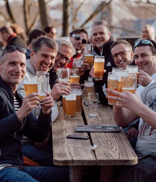 Freunde stoßen bei einer Biergarten-Wanderung auf dem Erlanger Brauereienweg mit Bier an