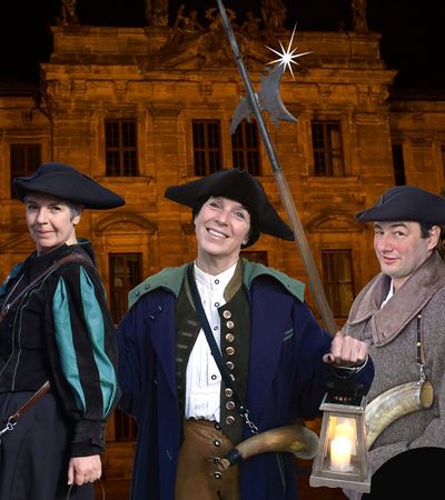 Erlanger Nachtwächter führt Touristengruppe durch nächtliche Altstadt, Laterne und Hellebarde in HandErlangen entdecken