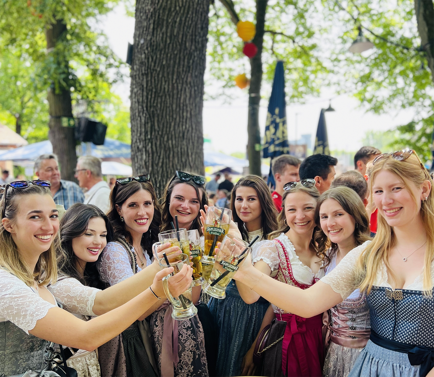 Freunde stoßen mit Bier auf der Erlanger Bergkirchweih 2026 unter Kastanienbäumen an