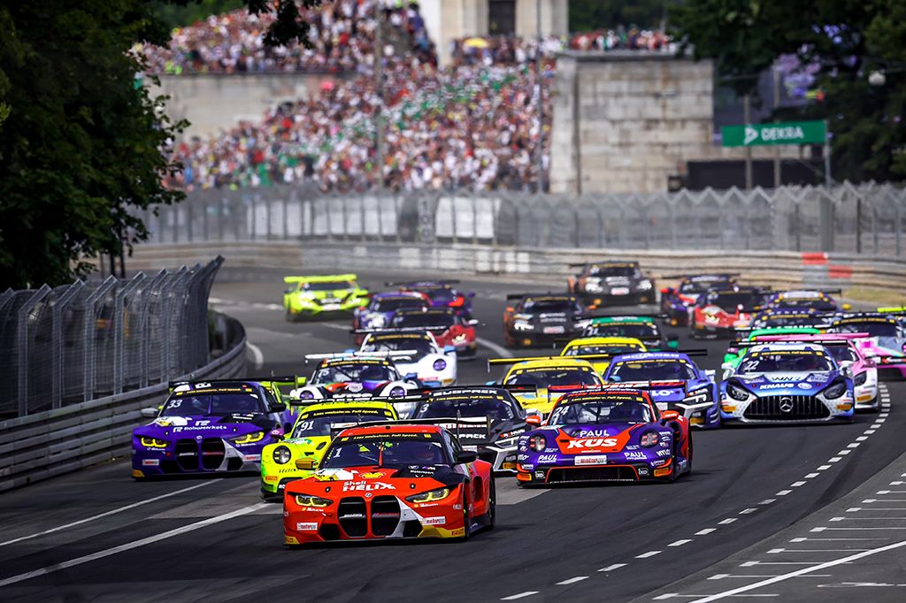 Actiongeladene Rennszene der DTM 2025 am Norisring: GT3-Fahrzeuge im Zweikampf auf der Strecke vor der Steintribüne.