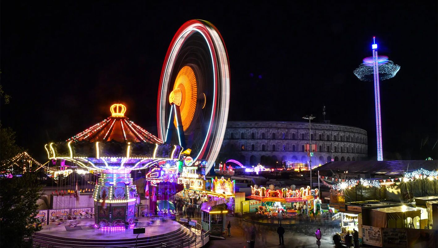 Die farbenfrohen Lichter der Fahrgeschäfte auf dem Nürnberger Herbstvolksfest erhellen die Nacht am Dutzendteich.