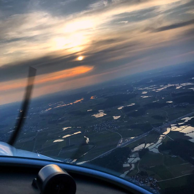 Rundflüge Herzogenaurach - Blick aus dem Cockpit eines Kleinflugzeugs während eines Rundflugs über Herzogenaurach bei Sonnenuntergang. Die untergehende Sonne spiegelt sich in den zahlreichen Seen und Teichen der Landschaft.