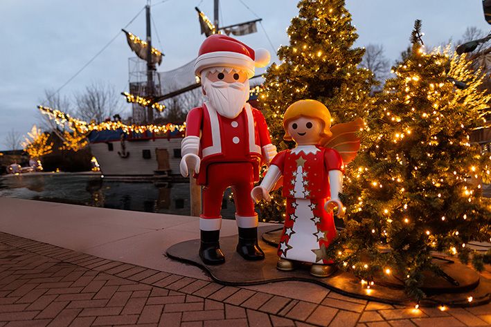 Winterlich dekorierter PLAYMOBIL-FunPark mit beleuchteten Themenwelten, Kindern beim Spielen und stimmungsvoller Winterzauber-Atmosphäre.