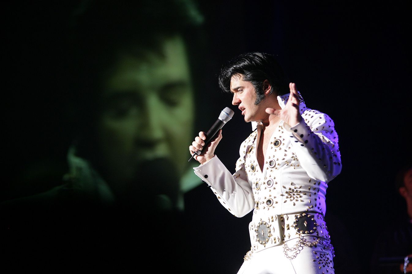 Grahame Patrick als Elvis Presley im weißen Bühnenoverall bei ELVIS – Das Musical auf der Bühne