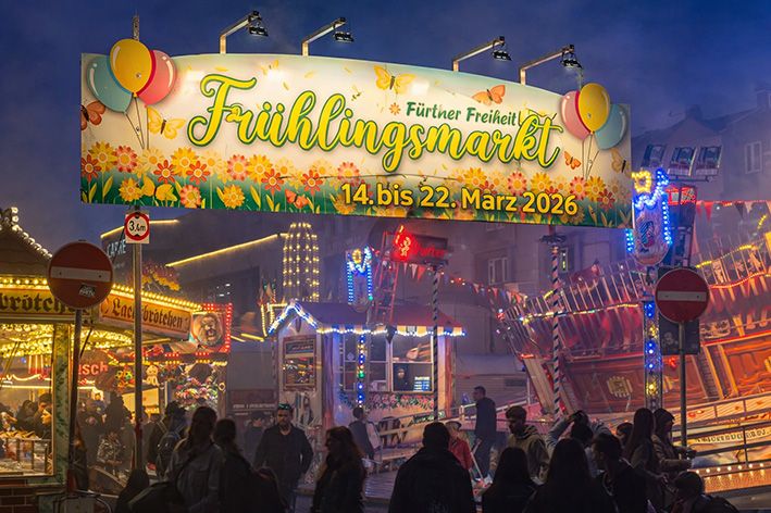 Fürther Frühlingsmarkt 2026 auf der Fürther Freiheit mit beleuchtetem Eingangsschild, Fahrgeschäften und Besuchern am Abend.