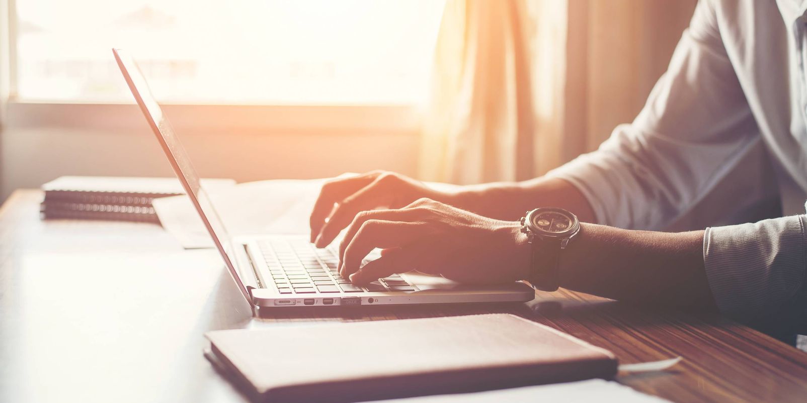 Close-up of male hands using laptop in home.