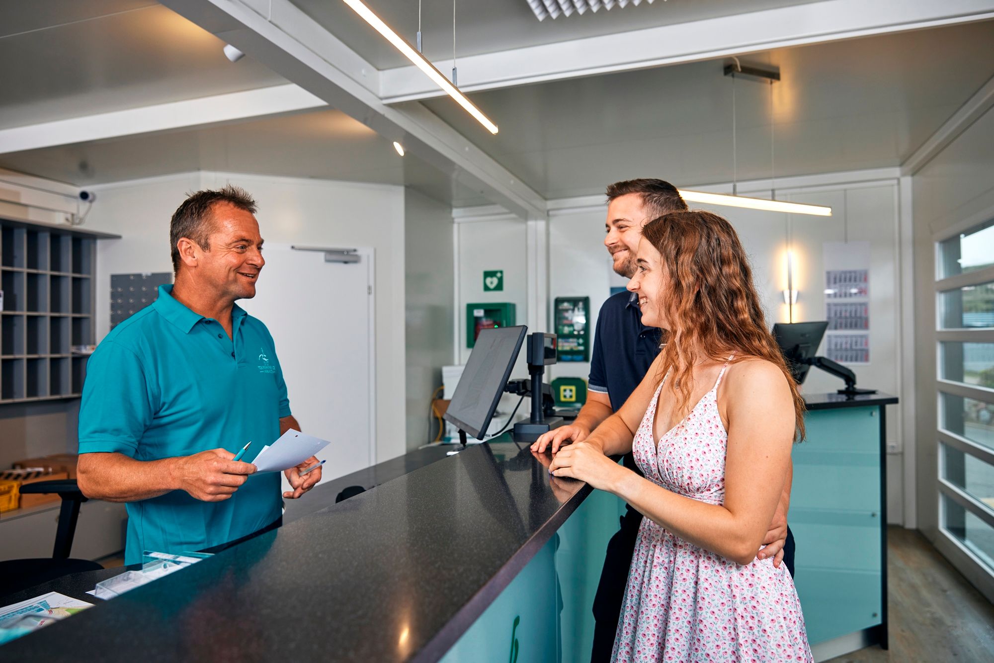 Junge Frau und Junger Mann erhalten Informationen vom Mitarbeiter des Campingplatzes Westerland