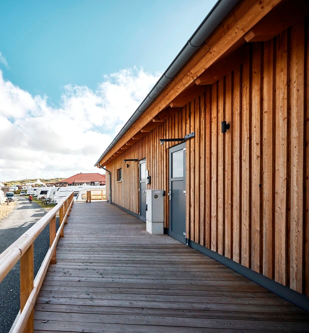 Seitliche Außenansicht des Sanitärgebäudes Nord auf dem Campingplatz Westerland sowie Ansicht einiger Stellplätze daneben
