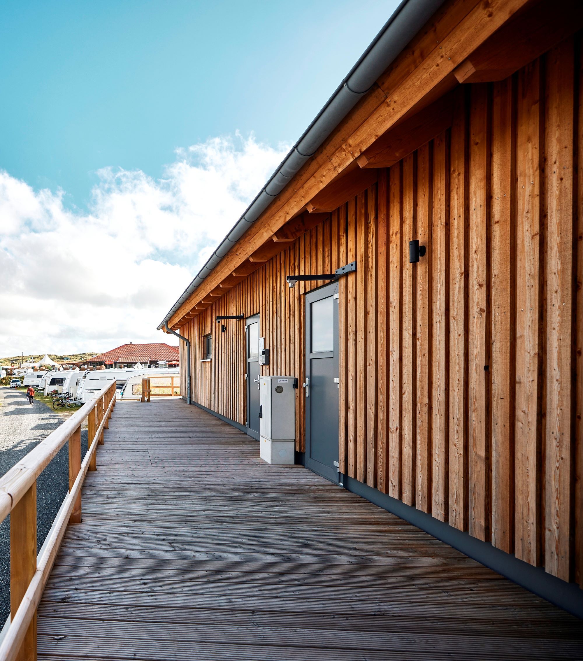 Seitliche Außenansicht des Sanitärgebäudes Nord auf dem Campingplatz Westerland sowie Ansicht einiger Stellplätze daneben