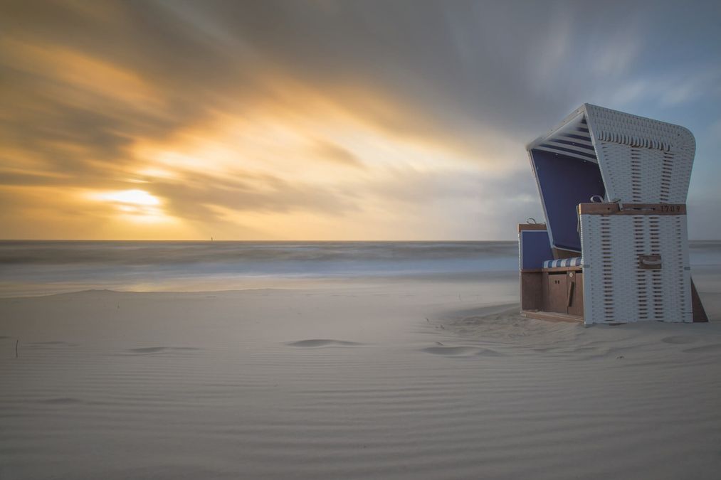 Einzelner Strandkorb am Strand bei Sonnenuntergang